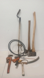 (1) Vintage Propane Flame Thrower (2) Wooden Handle Axes (1) Ridgid Adjustable Pipe Wrench (1) Bridgeport Hatchet With Sheaths (1) Antique Syth