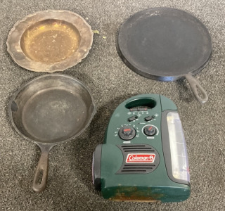 TWO CAST IRON PANS, ONE METAL PLATE, ONE COLEMAN AM/FM MINI LANTERN RADIO