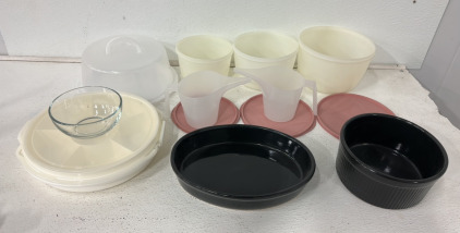 (3) Plastic Small Medium And Large Tupperware Bowls, (1) Cake Plate With Cover And Handle, (2) Black Glass Cooking Dishes, (2) Plastic Measuring Cups And More