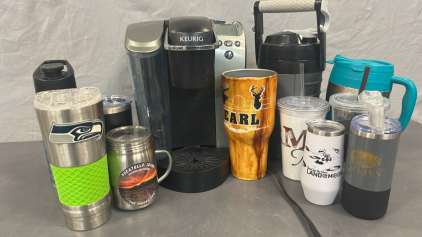 KEURIG COFFEE MAKER ( POWERS ON), IGLOO WATER BOTTLE AND TRAVEL COFFEE CUPS