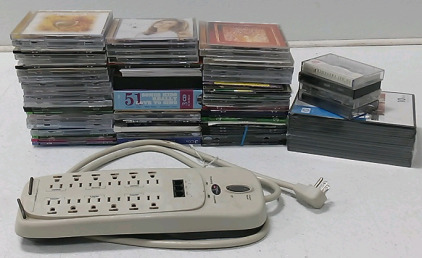(70) Assorted CDs (1) 12 Slot Surge Protector, (4) Assorted Cassette Tapes & More