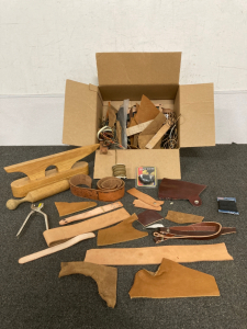 BOX OF LEATHERWORKING PIECES, INCLUDING STRINGS, LEATHER STRIPS AND PIECES, SALVE, AND TOOLS