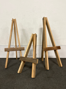 (3) WOODEN EASELS. TWO ARE 36" TALL AND (1) IS 24" TALL