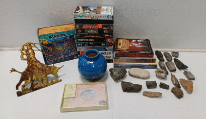 (11) Assorted VHS Including Armageddon, Speed, & Robin Hood (1) Embossed Ceramic Vase (1) Atlantis Puzzle (5) Spiritual Books (1) Hitch Cover (40) Assorted Rocks Including Some Petrified Wood & Agate Crystal & More