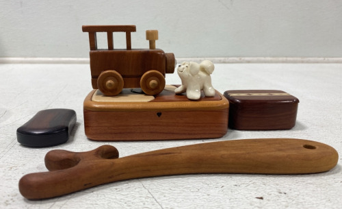 (1) Lot of Various Wooden Trinkets and Home Decor Such as; (1) Small Wooden Train (1) Wooden Puzzle Box (1) Porcelain White Dog (2) Small Wooden Containers, and more!