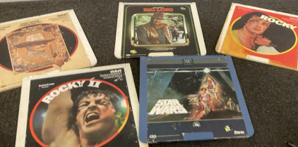 (5) CED DISC MOVIES, TWO JOHN WAYNE MOVIES (RIO LOBO, AND THE SHOOTIST), TWO ROCKY MOVIES (ROCKY 1, ROCKY 2), STAR WARS.