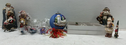 (2) Blue/Red Santa Holding Animals Statues, Large Hand Painted Lighthouse Ornament, (2) Ornate Clear Ornaments, Box of Small Miscellaneous Ornaments, Santa Riding Bald Eagle Statue, Wood Santa Statue, and More Holiday Decorations