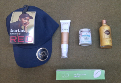 (1) Satin Lined Baseball Cap By Kiss, Navy, (1) Laura Geller Spackle Skin Perfecting Primer 2-FL Oz. , Bronze, (1) 3.2-Oz Jar Of Unicorn Dreams Whipped Bath Soap, (1) 3.4- FL Oz Bottle Of Zeitun Shimmering Body Oil & (1) 3-OZ Tube Of OLA Tulsi-Mint Toothp