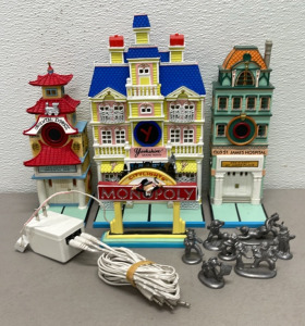 (3) Monopoly Department 56 Village Light Up Resin Buildings &ldquo;Law Offices Inc&rdquo;, &ldquo;Oriental Express&rdquo;, &ldquo;Old Saint James Hospital &ldquo;, &ldquo;Yorkshire Grand Hotel&rdquo;, W/ Plug And (7) Pot Metal Figurines And City Lights Town Sign.