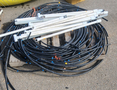 Pallet Filled With High-Density Polyethylene (HDPE) Pipes With Blue Drip Irrigation Emitters, And PVC Pipes