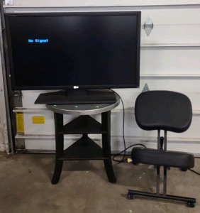 An LG 39" TV, a Black Message Chair, & a 24"x 24"x 27" Round Gray/Dark Red End Table