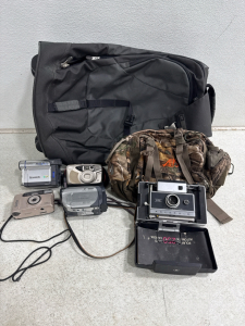 Vintage Polaroid, digital cameras, REI roller backpack, outdoor hip bag.