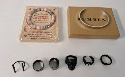 (8) Pieces Of Cosmetic Jewelry, (1) Rhodonite Bead Bracelet, (1) Stainless Steel Bracelet & (6) Black Finished, Fantasy Style Rings