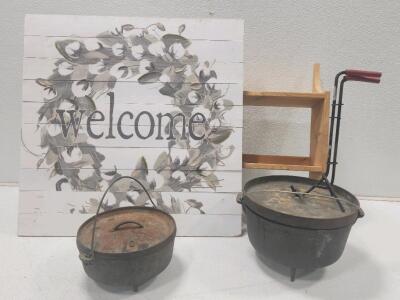 (1) Lodge Cast Iron Camp Dutch Oven (1) Vintage Cast Iron Camp Dutch Oven W/ Oven Lid Lifter (1) 24"H X 36"W X 7 1/4"D Wooden Wall Shelf (1) 30"H X 30"W Wooden Welcome Sign