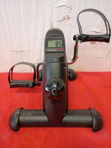 Mini Exercise Bike, Also Known As a Pedal Exerciser. It is a Compact Piece of Fitness Equipment Designed For Low-Impact Workouts For Both The Arms and Legs.