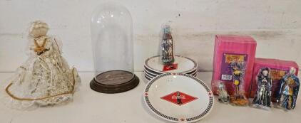 Mixed Collectors Lot with Coca-Cola Plates and Coke Bottle Figurines, Hunchback of Notre Dame Figurines, Glass Display Case, and an Angellic Figurine.