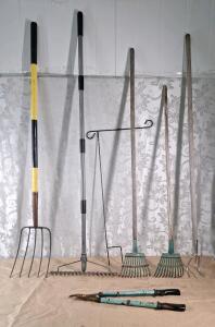 (1) Fiberglass Handled 5-Tine Pitchfork, (1) Metal Handled Level Headed Garden Rake, (2) Wood Handled Shrub Rakes, (1) Wood Handled 3-Tine Garden Weeder, (1) Limb Lopper & (1) Iron Garden Flag Holder