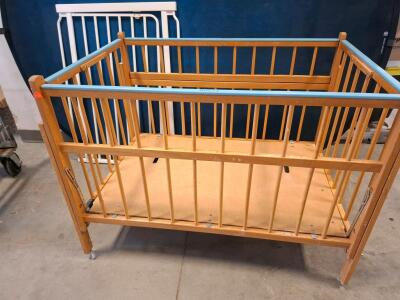 Portable Wood Crib With Wheels, Blue Accents, And White Metal Safety Gate