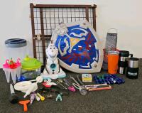 (XB) Mixed Collectible and Kitchen Lot: Legend of Zelda Shield Backpack, 3 Assorted Tupperwares, Plastic Pitcher, 3 Assorted Travel Coffee Mugs, Olaf Snowcone Maker, Popsicle Mold, Cheese Grater and Cheese Knife, Two Paring Knives, Baby Gate, 8 Sets of Co