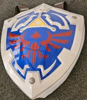 (XB) Mixed Collectible and Kitchen Lot: Legend of Zelda Shield Backpack, 3 Assorted Tupperwares, Plastic Pitcher, 3 Assorted Travel Coffee Mugs, Olaf Snowcone Maker, Popsicle Mold, Cheese Grater and Cheese Knife, Two Paring Knives, Baby Gate, 8 Sets of Co - 2