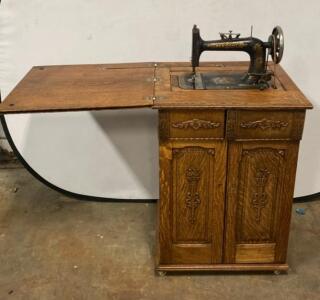 Antique New Home Treadle Sewing Machine with Ornate Oak Cabinet and Extension Leaf Circa 1900s