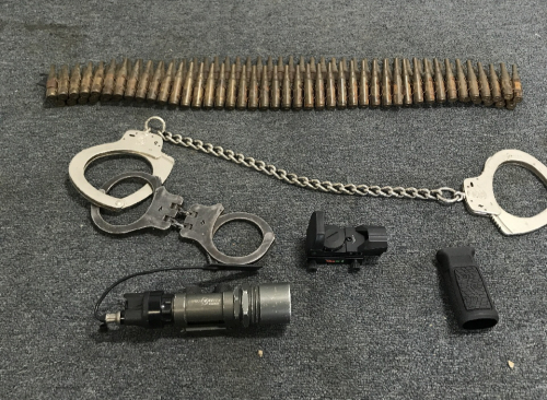 (1) Pair Smith And Wesson Leg Shackles (1) pair Peerless Handcuff Co Handcuffs (1) String Of Rifle Casings (1) Surefire Gun Light (1) TruGlo Gun Sight