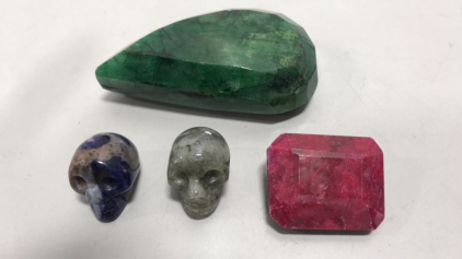 (1) Brazilian Pear Cut Emerald 538.8ct. - (1) Emerald Cut Madagascar Ruby 140.75ct. - (1) Sodalite Crystal Skull 54.7ct. - (1) Labradorite Crystal Skull 61.65ct.