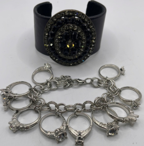 (1) Silver Toned Wedding Ring Charm Bracelet, (1) Leather And Brass Toned Bangle W/ Black Gemstones.