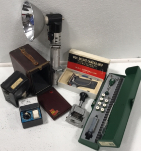 (1) Flash Meter (1) Camera Grip (1) Graflex Flash Handle (1) Fabre-Castell Lettering Set (1) Justrite Numbering Machine (1) Ansco Vintage Ansco Box Camera