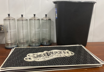 (1) Small Black Trash Can, (1) Stack of Suavectio pomade Mats, (4) Barbicide Disinfectant Containers Glass, and (1) Large Black Laundry Basket
