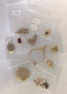 (2) 10 count 14KT Gold Filled Lobster Clasp ; (1) Square Cut Ruby Pendant ; (1) Heart Shaped Gold Pendant ; (1) Small Circle Cut Ruby Pendant ; (1) Small Gold Cross ; (1) Small Gold Circle Pearl Pendant ; (1) Small Oval Gold w/ Pearl Pendant ; (1) Small E